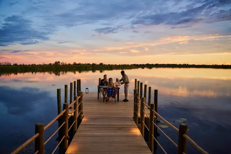 Dinner at the end of a wooden jetty on Xugana Lagoon at sunset